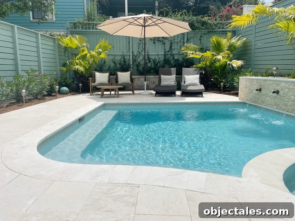 Completed small freeform pool filled with water with curved edges and tropical landscaping
