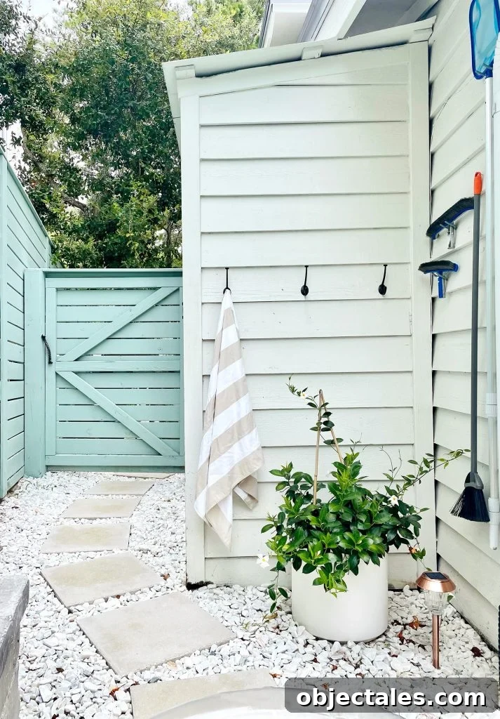 Hook towel storage along white shed and pool skimmer hanging on hooks on house siding