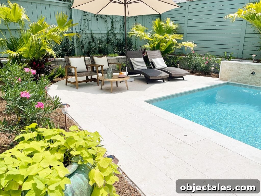 Backyard pool with sitting area under umbrella surrounded by tropical plants